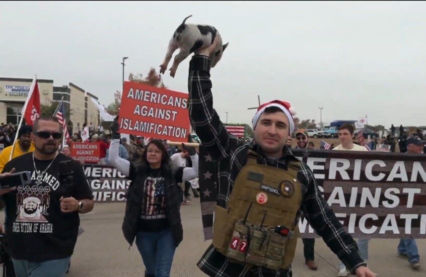 أمريكي يضع نسخة من القرآن الكريم في فم خنزير خلال احتجاج مناهض للإسلام في تكساس (فيديو)